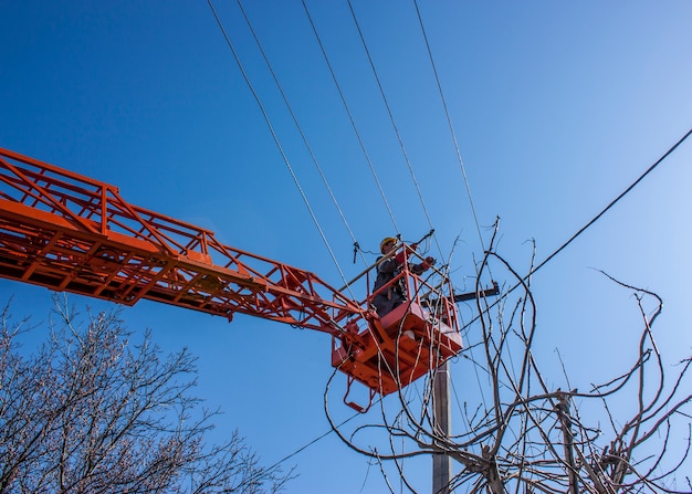 Photo lineman duty working fix power line on electrical cable with aerial work platforms