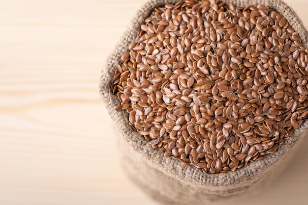 Linen grain in sack against wooden background Fresh linen grain used for adding in bakery