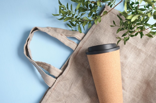 Photo linen shopping eco bag and thermo coffee cup on blue background hand made reusable shopping bag, zero waste concept, eco friendly life style top view