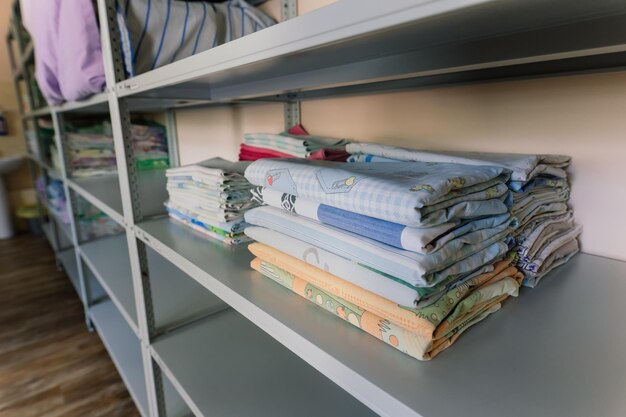 Linens piled neatly on shelves There are folded bed sheets towels wash clothes