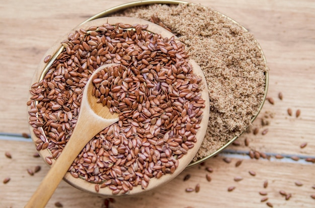 Linseed grain and milled flax in wooden little spoon and bowl.Natural cereal