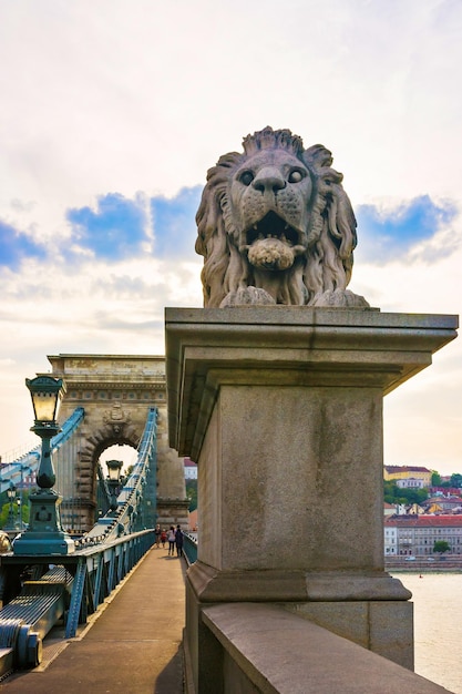 Lion sculpture on the Szechenyi Chain Bridge, Budapest, Hungary. People on the bridge