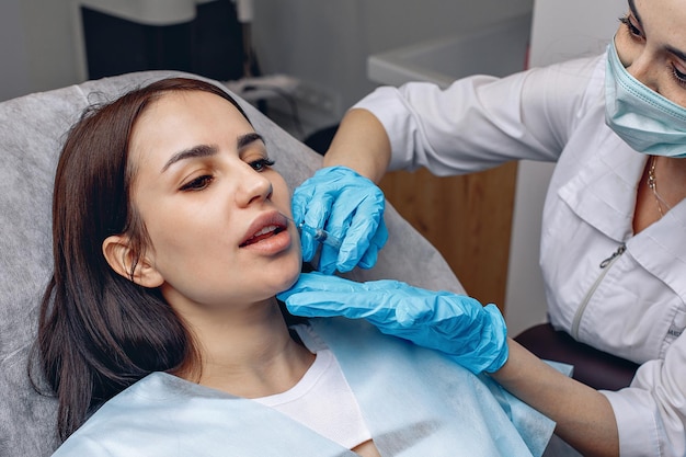 A lip augmentation in a spa salon. A beautician gives injections to a young woman. Beauty procedure.