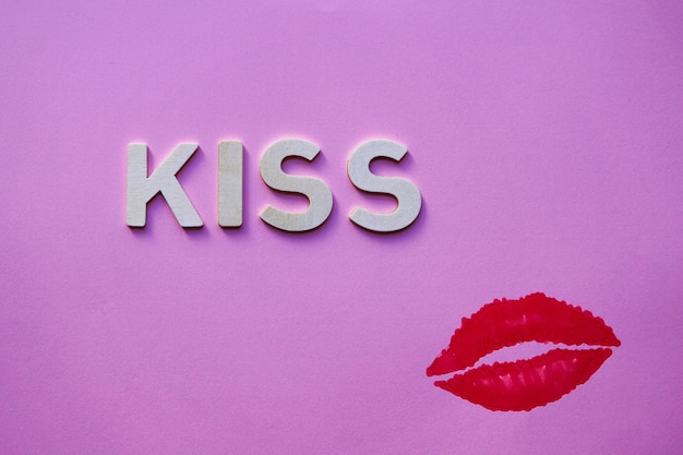 lips and kiss word with wooden letters on the pink background