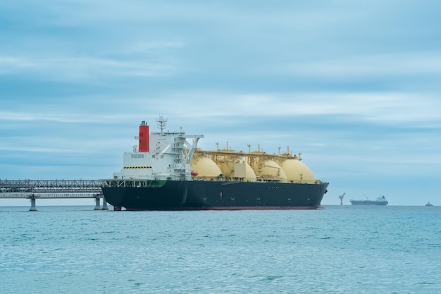 Liquefied natural gas carrier tanker during loading at an LNG offshore terminal in the distance the oil export terminal is visible in the sea