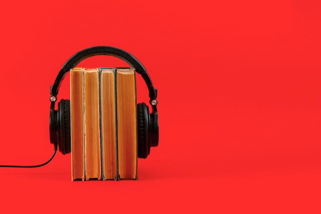 The listen to the audio books concept, big headphones put on the stack of books isolated, simple style