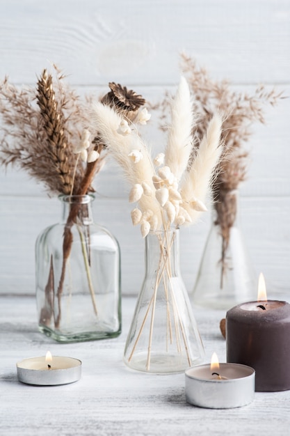 Lit aroma candles and dry flowers on rustic table. Spa arrangement in monochrome style