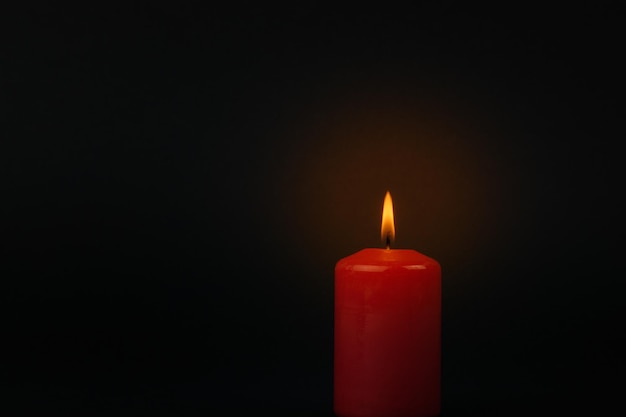 Lit a beautiful red candle on a black background.