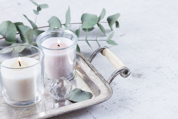 Lit candles and green leaves on a tray