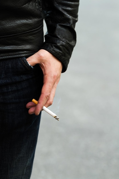 A lit cigarette in a man's hand