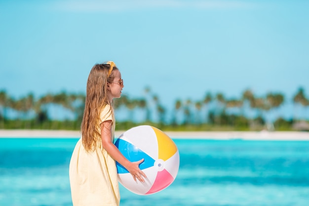 Little adorable girl playing on beach with ball