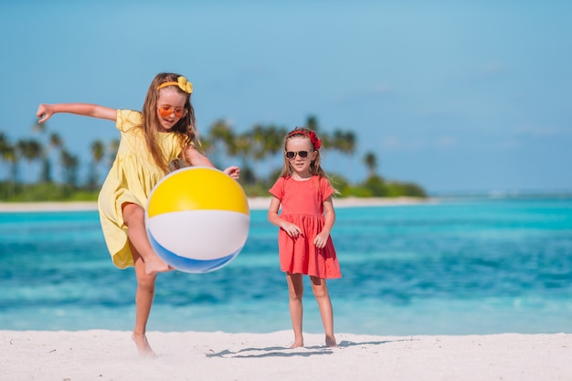 Little adorable girls playing on beach with air ball