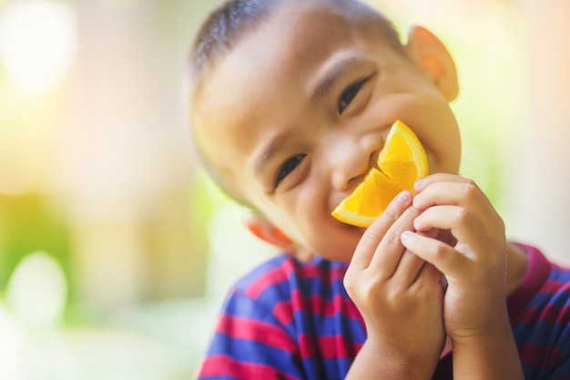 Little asian boy use a slice of orange for smiling face