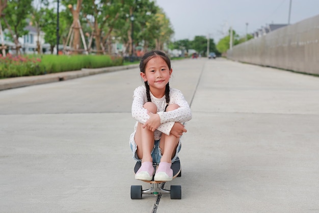 Little Asian child playing on skateboard Kid riding on skateboard outdoors at the street