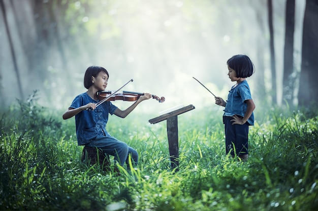 Little Asian child playing violin at outdoors