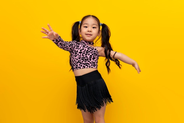 little asian girl in dance outfit dances chachacha on yellow isolated background korean child dancer