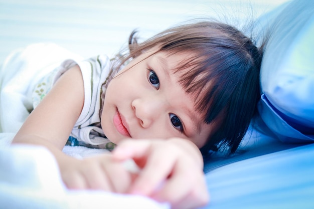 A little Asian girl is sick with a fever She was lying on the bed in the hospital examination room concept of children's disease viral infection medical services