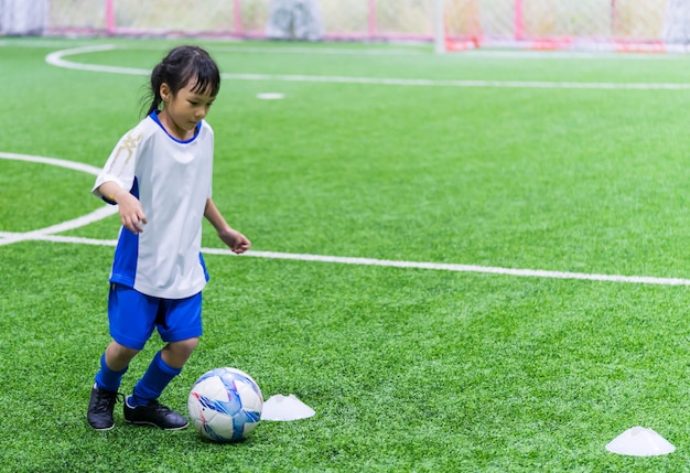 Little Asian girl is training in indoor soccer field