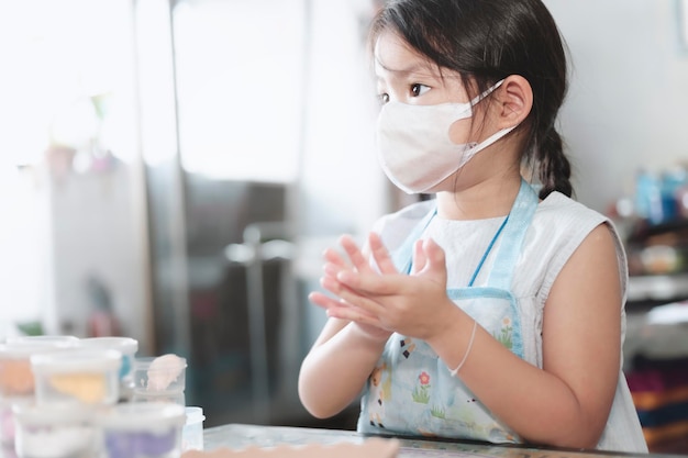 Little Asian girl playing with plasticine at home