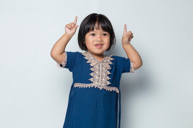 Little asian girl pointing with fingers to different directions Copy space for advertisement