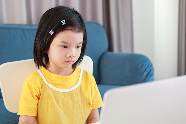 Little asian girl student study online using laptop computer at home