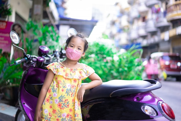 Little asian girl wearing a mask against dusk and covid-19 outdoor