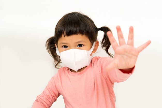 Little asian girl  wearing mask for protect pm2.5 and show hand stop