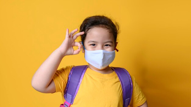 Little asian girl wearing mask for protect pm25 and Covid19 with OK finger hands gesture