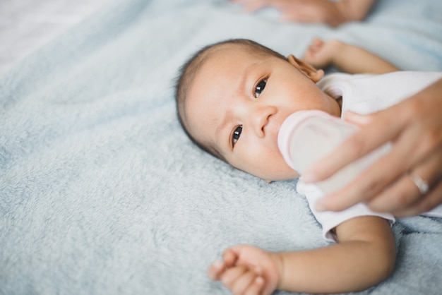 Little asian newborn baby boy sleep and drinking milk on a comfortable bed in the morning