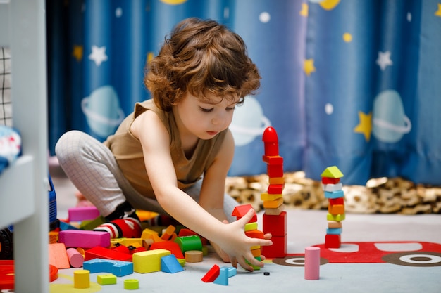 Little autistic boy playing with cubes at home