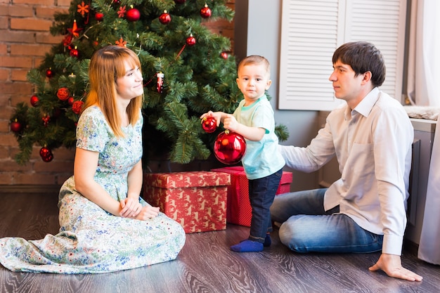 Little baby boy decorating a Christmas tree toys. Holidays, gift, and new year concept.