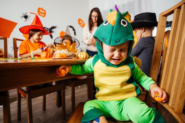 Little baby boy in green fancy costume sitting and crying