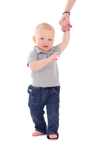 Little baby boy walking and holding mother's hand isolated on white background