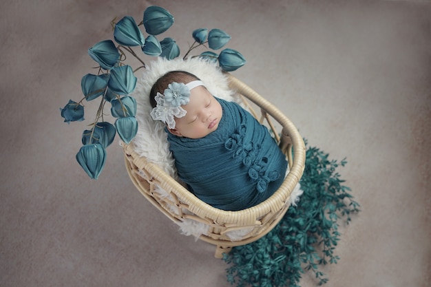 Little baby covered in blue clothes with bandage on his head lying sleeping on white pillow