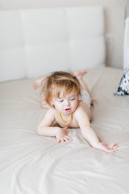 Little baby in a diaper lies on the bed and laughs