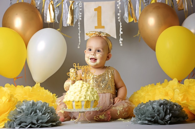 Little baby girl eating birthday cake during cake smash party