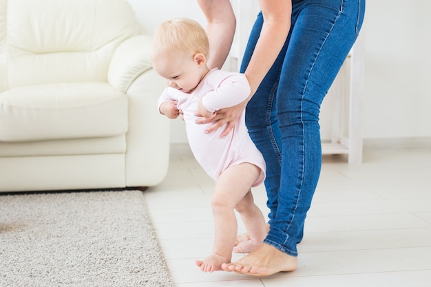 Little baby girl first steps with the help of mom