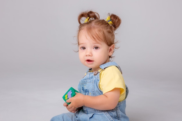 little baby girl is on a white background and playing with colorful cubes kid's play toy cubes