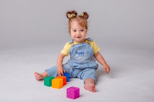 little baby girl is on a white background and playing with colorful cubes kid's play toy cubes