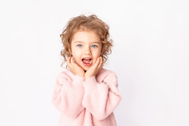 Little baby girl in pink winter clothes on white background rejoices, space for text