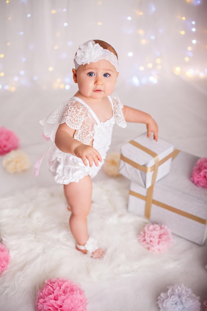 Little baby girl staying among a lot of gift boxes celebrating birthday or christmas