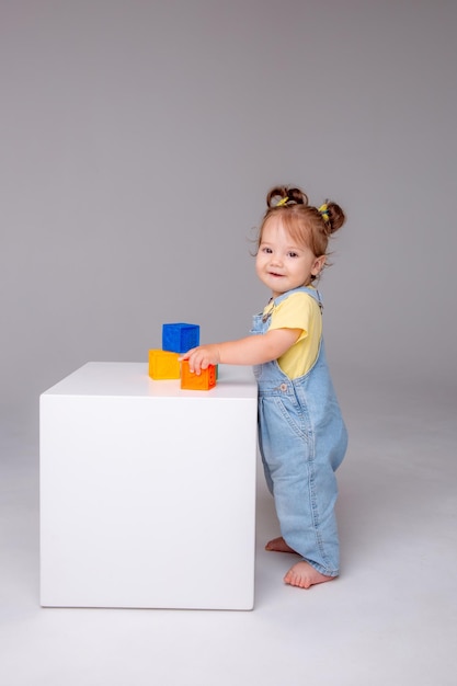 little baby girl  on a white background and playing with colorful cubes. kid's play toy cu