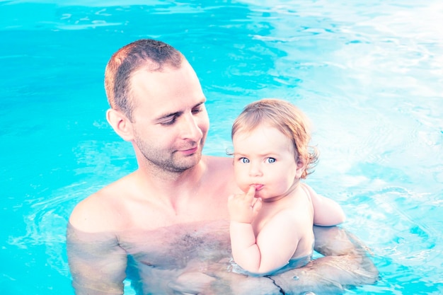 Little baby girl with father in a pool Learn baby swimming concept