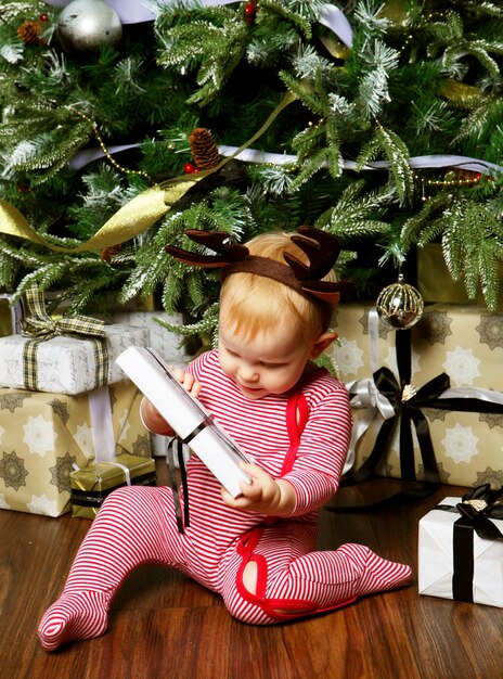 Little baby girl with the gift box near Decorating Christmas tree. Happy time.