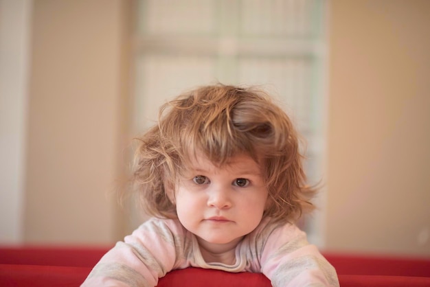 little baby girl with strange hairstyle and curlers in bed at home