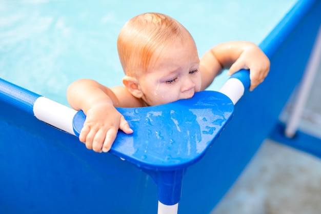 Little baby have a fun with a splash in swimming pool.