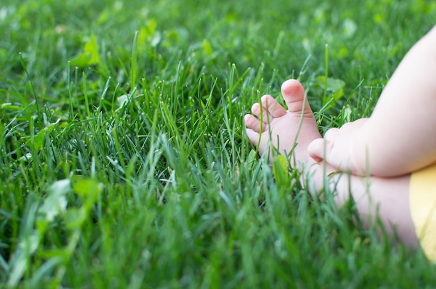 Photo little baby legs on a green lawn in the park