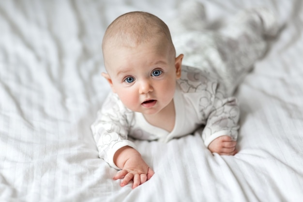 A little baby lying on the bed on a white sheet