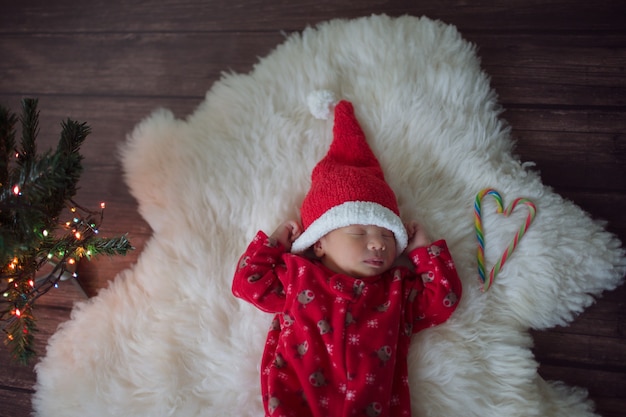 Little baby in red cap of Santa Claus celebrates Christmas