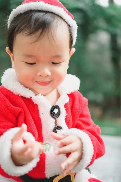 Little baby with Santa Claus outfit on floor